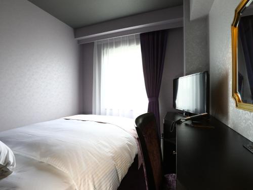 a bedroom with a bed and a tv and a window at Hotel Wing International Select Osaka Umeda in Osaka