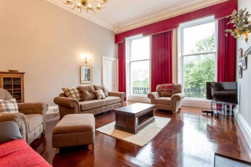 a living room with red curtains and a couch and a table at JOIVY Spacious Apt in New Town Prime Location in Edinburgh