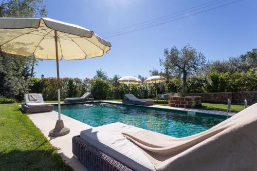 a swimming pool with an umbrella and lounge chairs and an umbrella at Villa Ligheia in Gambassi Terme