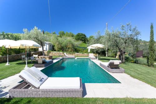 a pool with chairs and umbrellas in a yard at Villa Ligheia in Gambassi Terme