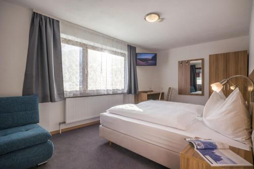 a bedroom with a white bed and a blue chair at Frühstückspension Sport Mayr in Söll