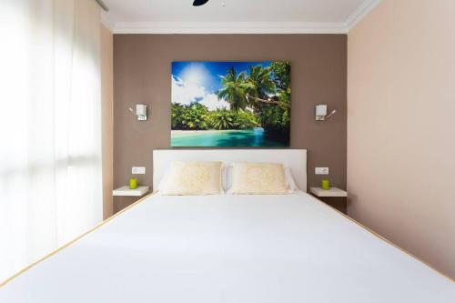 サンミゲル・デ・アボナにあるApartamento Amarilla Golfのベッドルーム1室(壁に絵画が描かれた白い大型ベッド1台付)