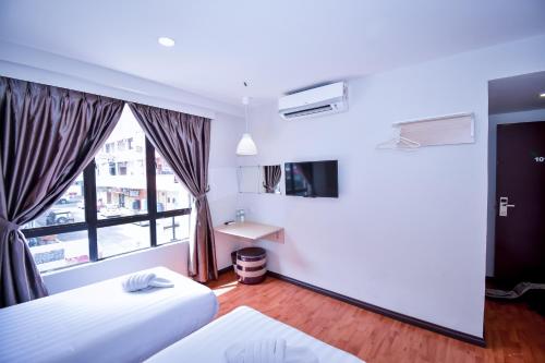 um quarto de hotel com duas camas e uma janela em Eden Boutique Hotel em Tawau