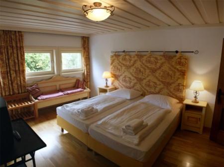 a bedroom with a large bed and two windows at Landgasthof zum Scheiber in Sirnitz