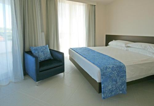 a bedroom with a large bed and a chair at Blu Suite Resort in Bellaria-Igea Marina