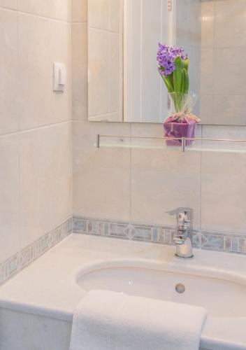 a bathroom with a sink with a vase of purple flowers at Family Hotel Belle Epoque Beach in Varna City