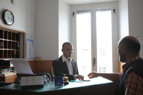dos hombres sentados en un escritorio en una oficina en Hotel Dorico, en Ancona