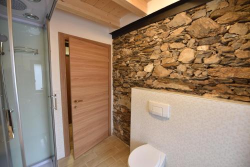 a stone wall in a bathroom with a toilet at Antica Casa Nella in Venas