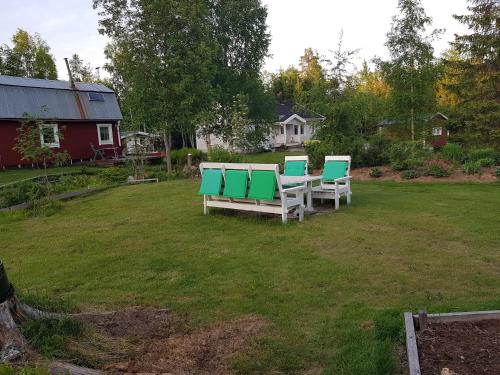 three green and white chairs sitting in a yard at Hyttingsfabodstugor in Borlänge