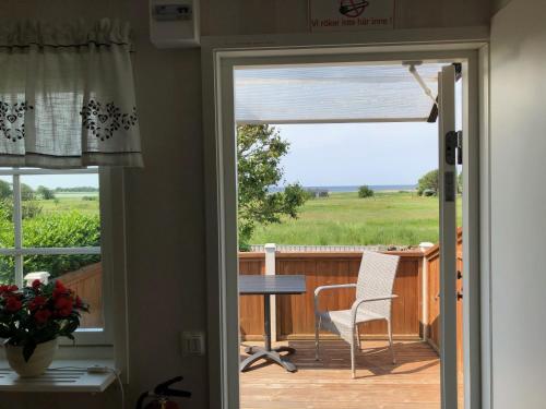 une porte menant à une terrasse avec une table et une chaise. dans l'établissement Lillstugan, à Kärradal