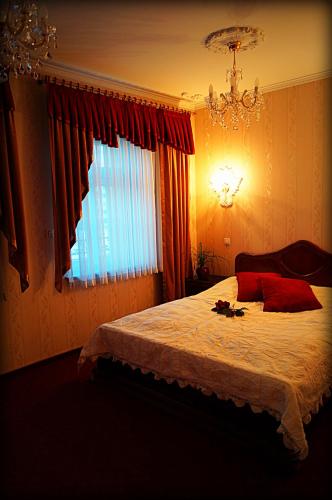 a bedroom with a bed with a chandelier and a window at Hotel Zaodrze in Opole