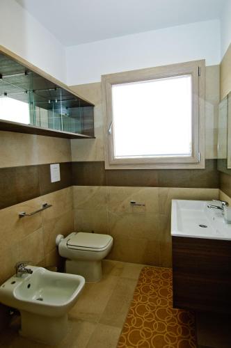 a bathroom with a toilet and a sink and a window at Villa Marianna in Castiadas