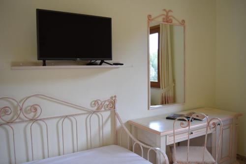 1 dormitorio con 1 cama y TV en la pared en Hotel Soffio di Vento, en Arbus