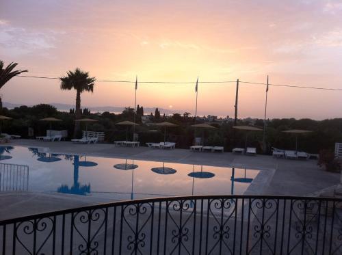 a view of a swimming pool at sunset at Ampavris Family Apartments in Kos Town