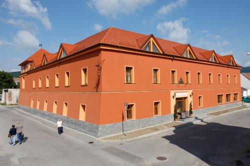 a large orange building with people walking around it at Hotel Majolika in Modra