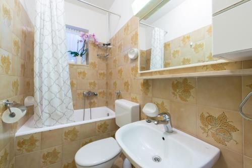 a bathroom with a sink and a toilet and a mirror at Apartman Lu in Mokošica