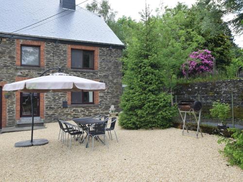 a patio with a table and chairs and an umbrella at Country house in the Ardennes with Schwimmbad in Warempage