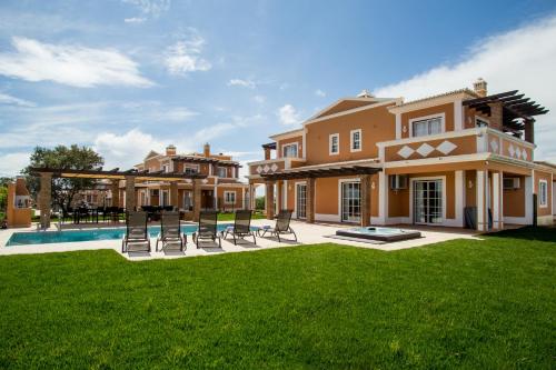 a large house with a yard with chairs and a pool at Colina da Lapa & Villas in Carvoeiro