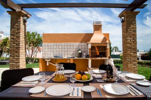 a table with plates and glasses on a table with a fireplace at Colina da Lapa & Villas in Carvoeiro