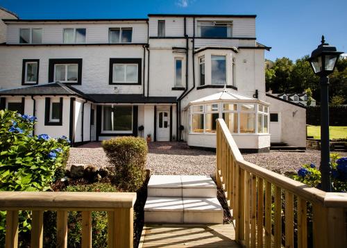 duży biały dom z gankiem i ogrodzeniem w obiekcie Lochside Guest House w mieście Arrochar