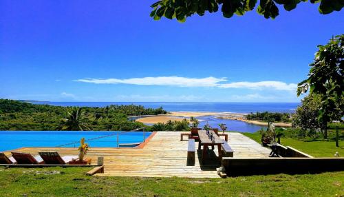 una terraza de madera con bancos y vistas al océano. en Bela Vista Hotel Boutique, en Caraíva