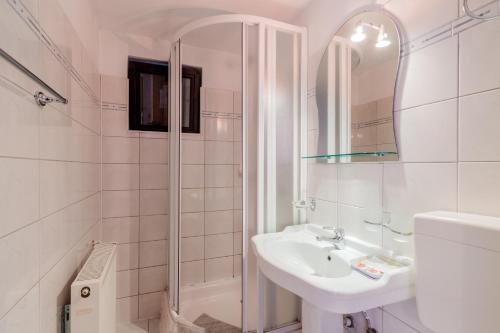 a white bathroom with a sink and a shower at Pensiunea Alis in Călimăneşti