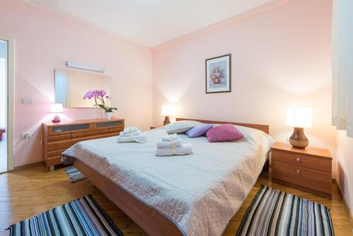 a bedroom with a large bed with towels on it at Apartman Lu in Mokošica