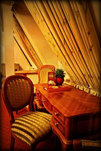 a wooden table with two chairs and a table with a plant on it at Hotel Zaodrze in Opole