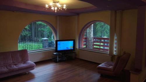 a living room with two arched windows and a flat screen tv at Casa de vacanța in Paraul Rece