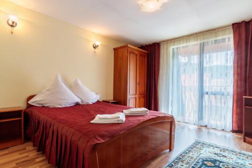 Un dormitorio con una cama con sábanas rojas y una ventana en Pensiunea Alis en Călimăneşti