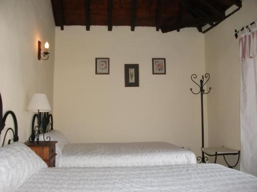 Dos camas en un dormitorio con sábanas blancas. en Casa la Vistita, en Guía de Isora