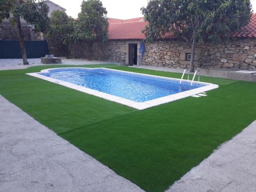 uma piscina com relva verde ao lado de um edifício em Casa Dos Lagares De Vara E Pedra em Vila Flor