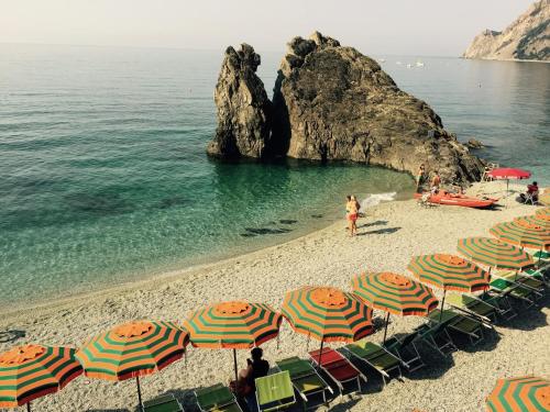 - un groupe de parasols et de chaises sur une plage dans l'établissement Acciuga, à Monterosso al Mare