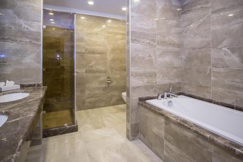 a bathroom with a tub and a shower and a sink at Maristella Marine Residence in Odesa