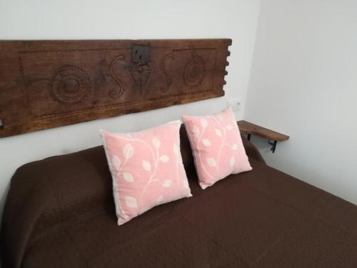 um quarto com uma cama com duas almofadas cor-de-rosa em Pico San Carlos ll em Bejes