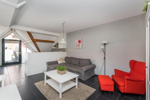a living room with a couch and red chairs at Weststraat 22 - Ouddorp - Appartement Oost 3P in Ouddorp