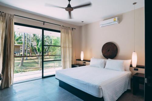 a bedroom with a bed and a large window at Beachfront TalingNgam in Taling Ngam Beach