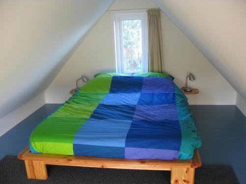 a bed with a colorful comforter in a room at Villa Selva in Loppersum