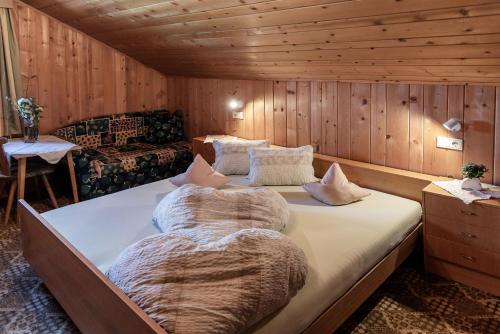 a large bed in a room with wooden walls at Oberhabererhof in Santa Maddalena in Casies