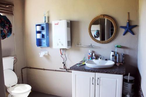 uma casa de banho com um lavatório, um WC e um espelho. em Seaview Cottage em Coffee Bay