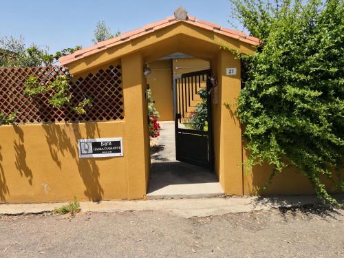 a small yellow building with a black door with a sign at B&B Gassa d'Amante in Capoterra