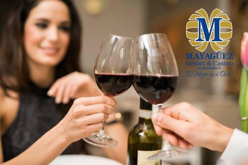two people holding up glasses of red wine at Mayaguez Resort & Casino in Mayaguez