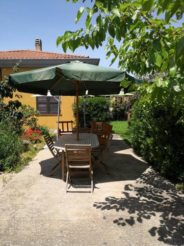 a table and chairs under a green umbrella at B&B Gassa d'Amante in Capoterra