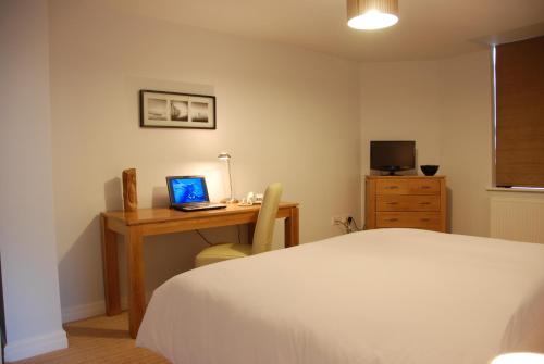 a bedroom with a bed and a desk with a laptop at The Port House in Heysham