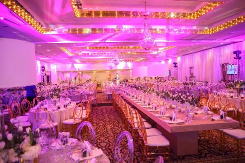 a banquet hall with white tables and chairs and purple lighting at Mayaguez Resort & Casino in Mayaguez