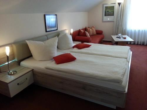 a bedroom with a large bed with red pillows at Hotel-Pension Deter in Wernigerode