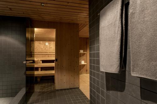 ein Badezimmer mit schwarzen Fliesenwänden und einer Holztür in der Unterkunft T3 Alpenhotel Flims in Flims