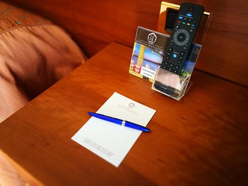 a table with a remote control and a pen on it at Hotel Lido - Beach and Palace in Bolsena