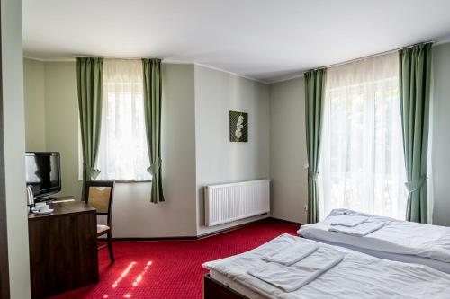 a bedroom with two beds and a desk and a television at Hotel Walewscy in Gdańsk-Rębiechowo