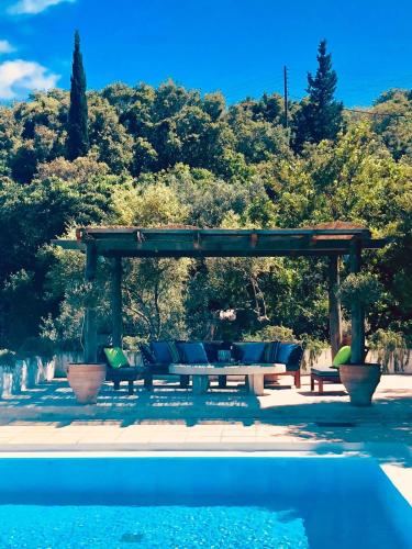 Eine Pergola mit Sofas und einem Tisch neben einem Pool in der Unterkunft Storeali in Skinária